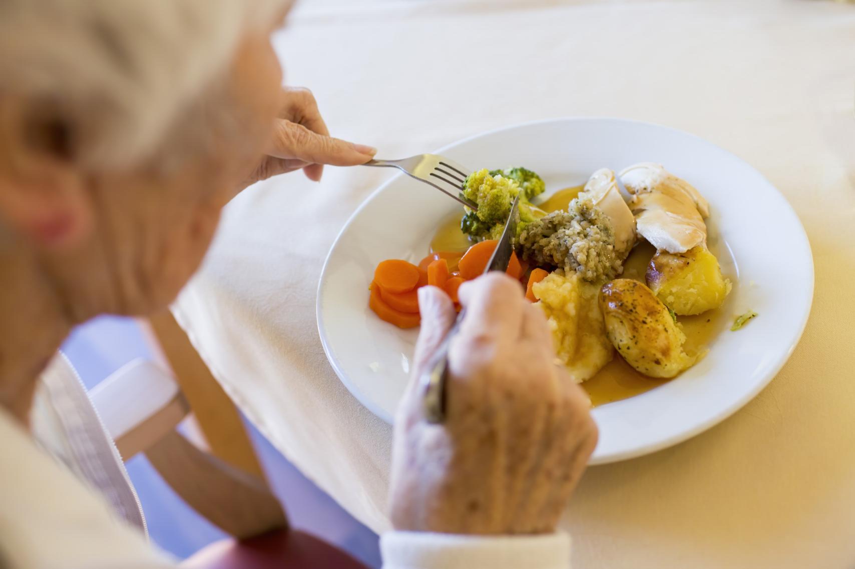 Elderly Woman eating her sunday roast dinner