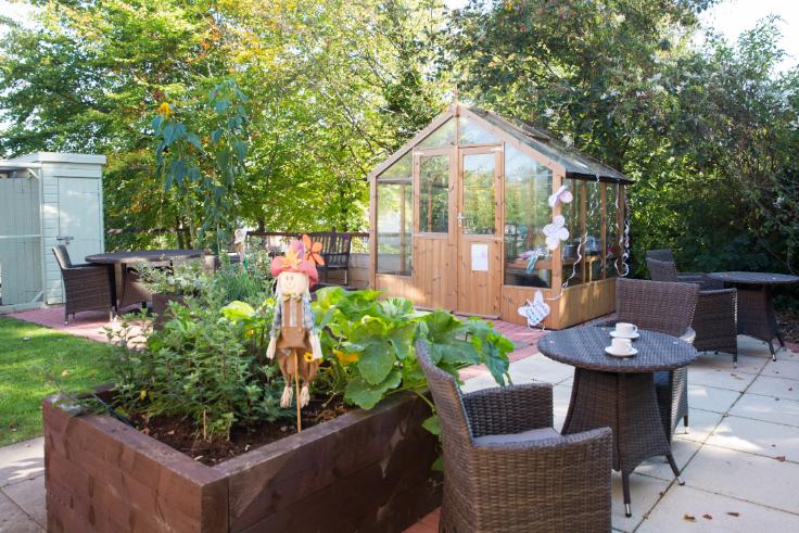 Garden area with green house and scarecrow at Bowood Court Care Home