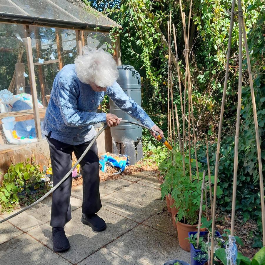 resident in blue jumper hosing plants
